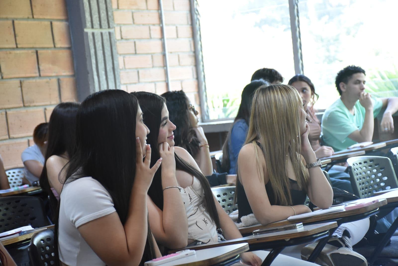 Estudiantes atentos durante una jornada del Pre Saber, sentados en un aula junto a un ventanal.